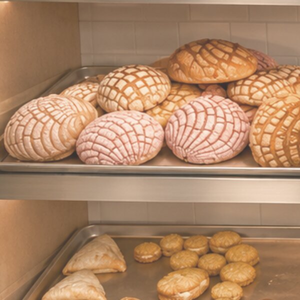 Pink and vanilla conchas stacked on a tray at San Diego Bakery